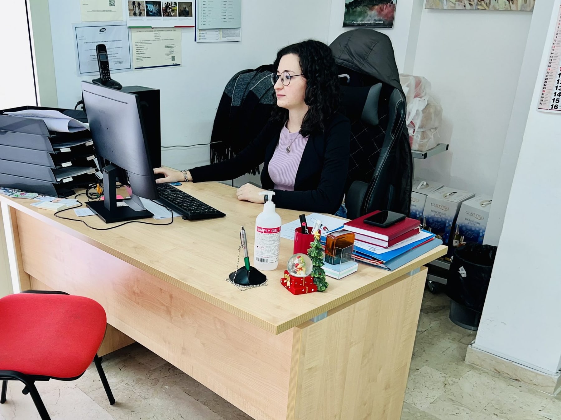 La postazione di accoglienza della sede, con la scrivania della segreteria e la sedia per chi attende