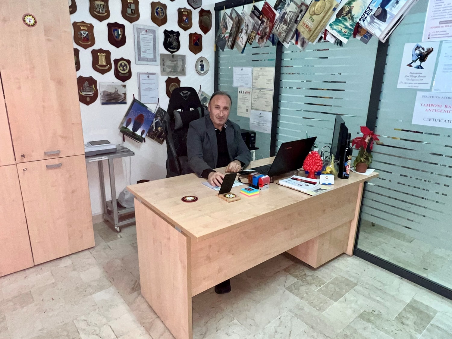 Maurizio Ferrara, presidente dell’associazione, alla scrivania della sede di via Nairobi, davanti alla parete dei riconoscimenti